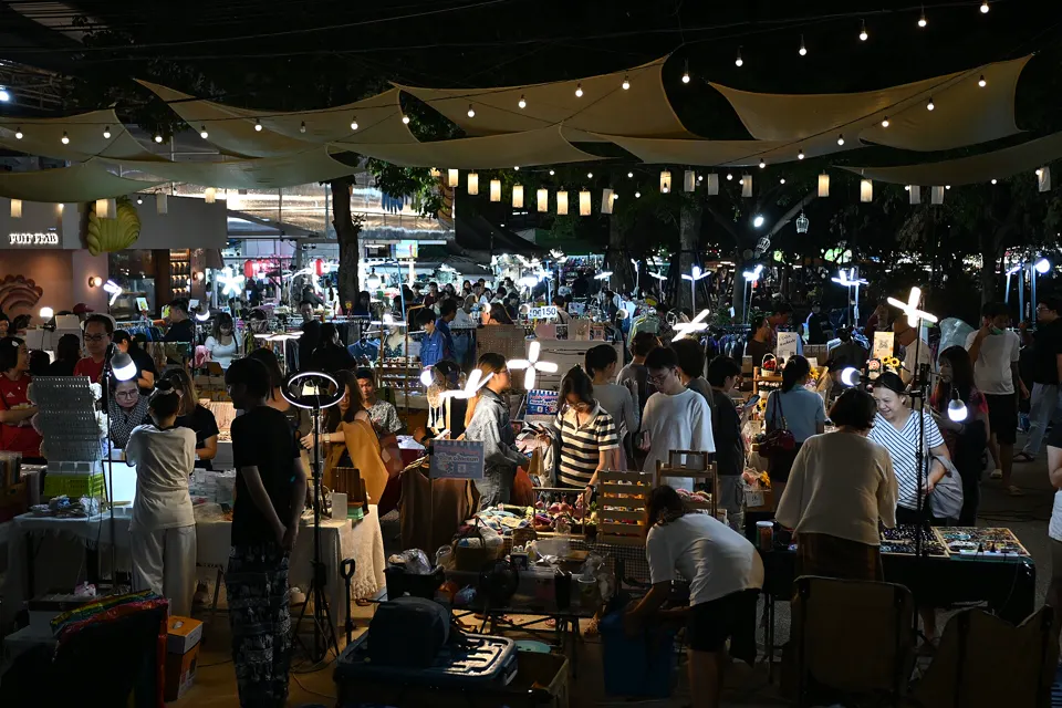 DFC 2582 A bustling night market filled with vendors and shoppers under strings of lights and fabric canopies